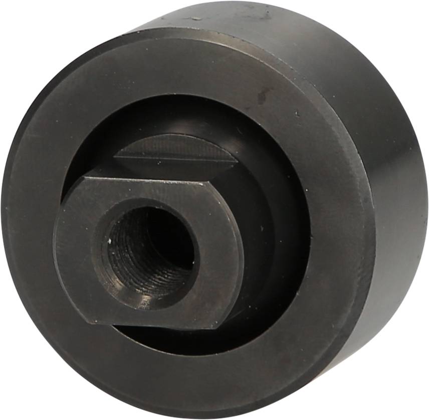 Czarny element metalowy o kształcie cylindrycznym z centralnym otworem i wystającą kanciastą strukturą, prawdopodobnie część mechanizmu.