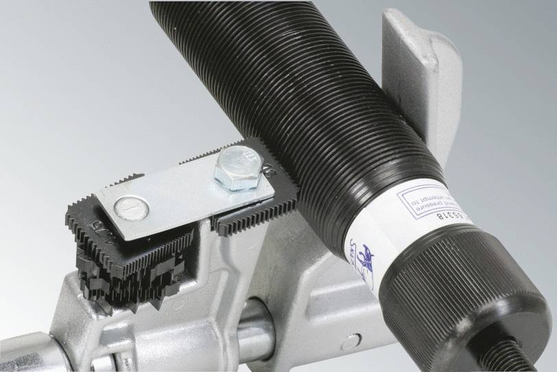 Metalowy element z śrubami i mechanicznym mechanizmem; prawdopodobnie część przemysłowej maszyny lub wyposażenia.