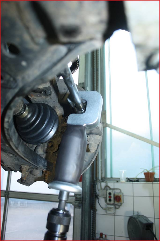 Narzędzie mechanika podczas pracy przy kole samochodu. Ściągacz usuwa sworzeń przegubu kulistego z zawieszenia.