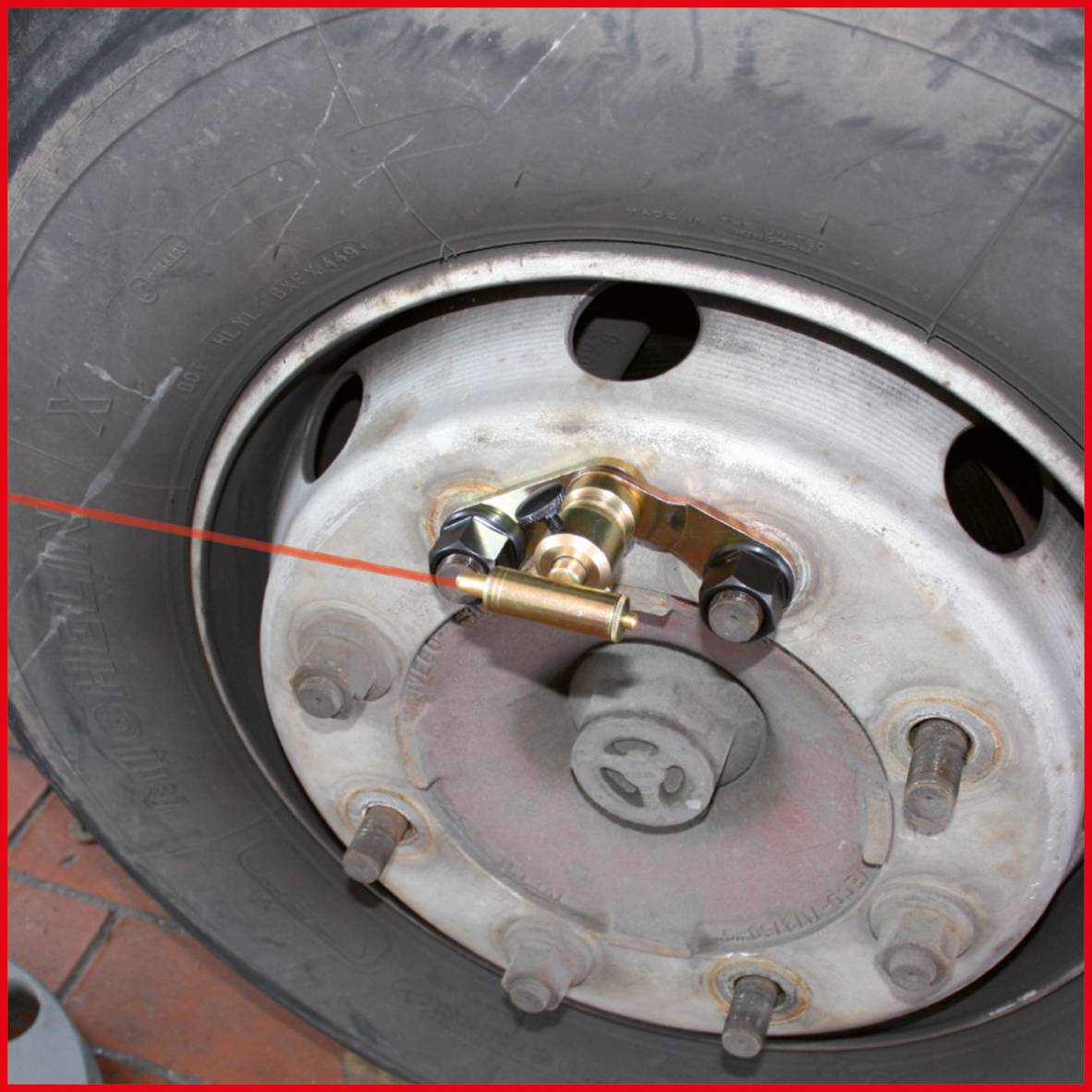 Zbliżenie opony ciężarówki z czerwoną linią laserową używaną do sprawdzania ustawienia osi.