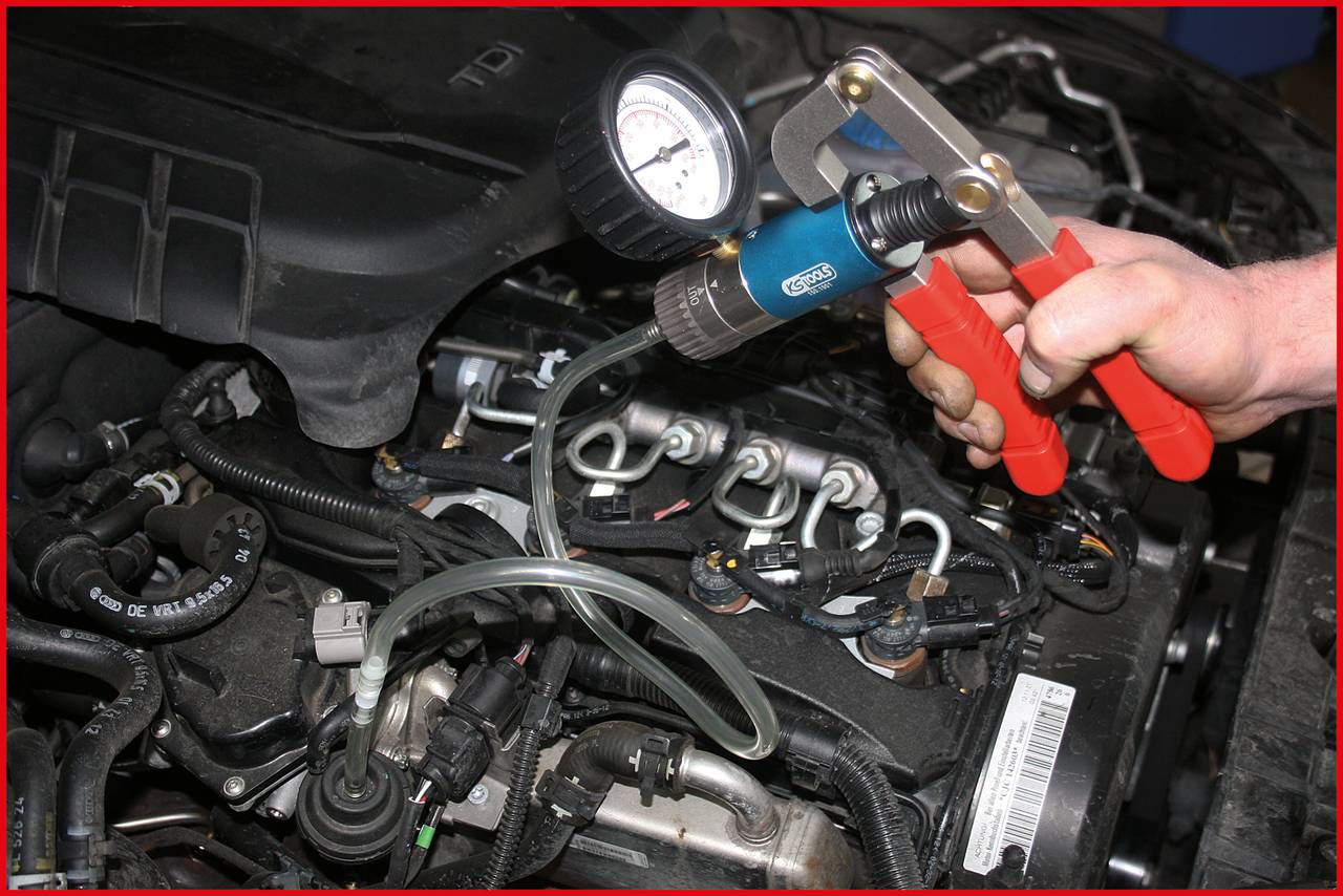 Osoba używa narzędzia pompy próżniowej do testowania ciśnienia w układzie paliwowym samochodu. W tle widoczny jest przedział silnika.