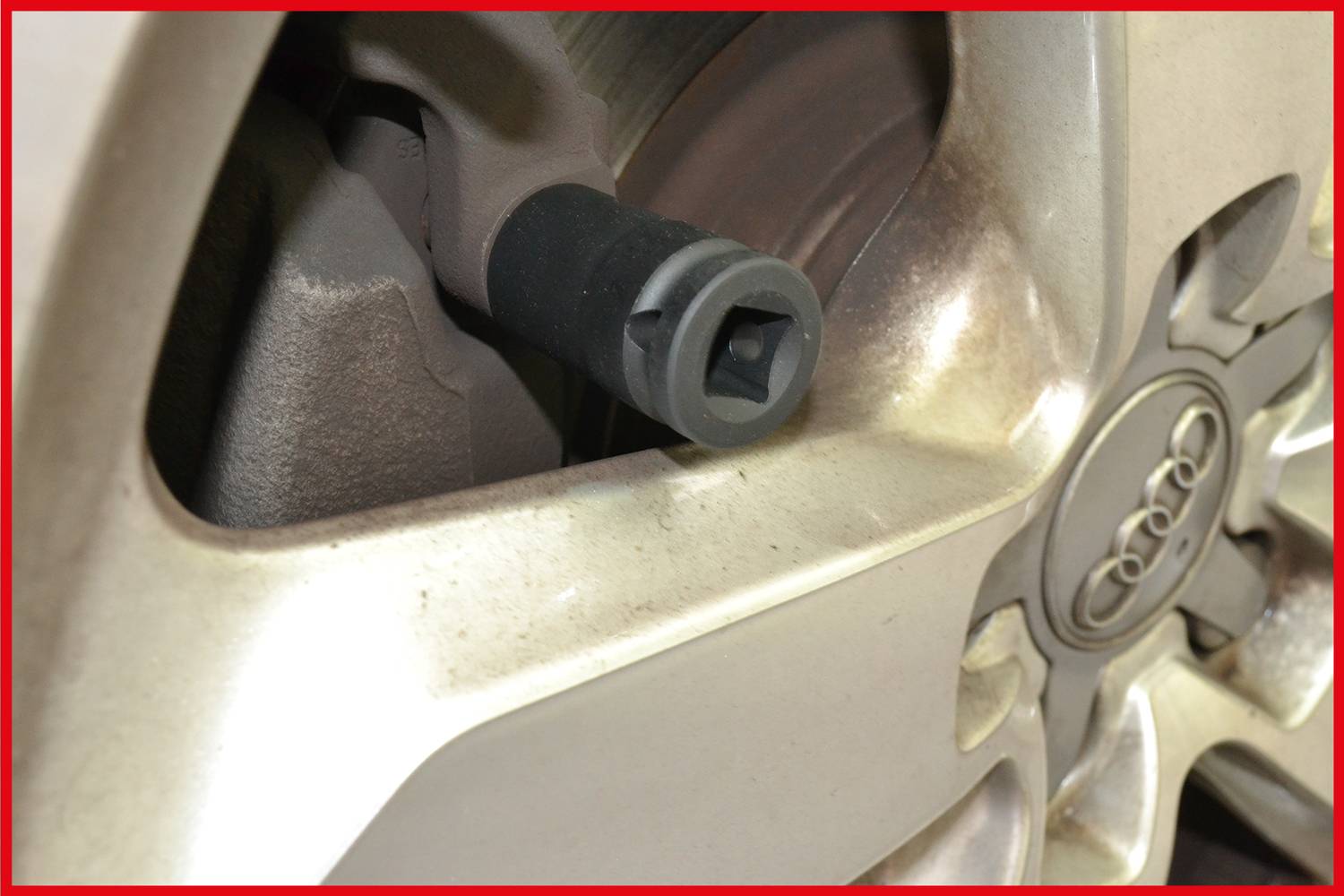 Zbliżenie zaworu opony, otoczonego srebrnym obręczem koła z logo marki samochodu pośrodku.