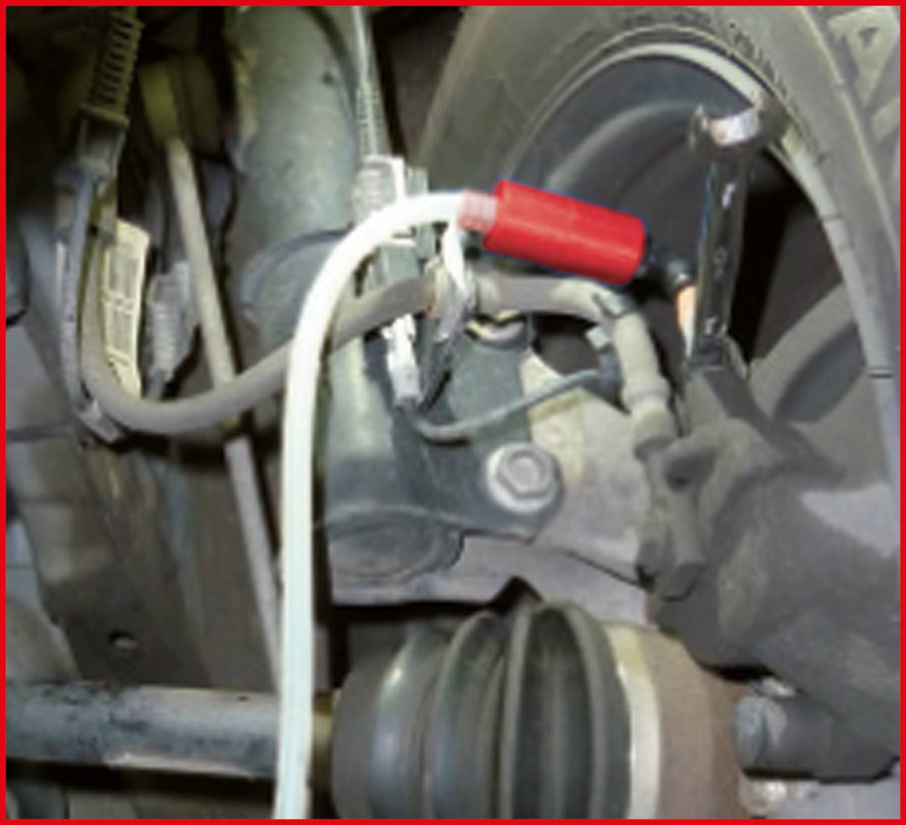 Klucz płaski i przewód są przymocowane do elementu pojazdu. Scena przedstawia fragment procesu naprawczego.