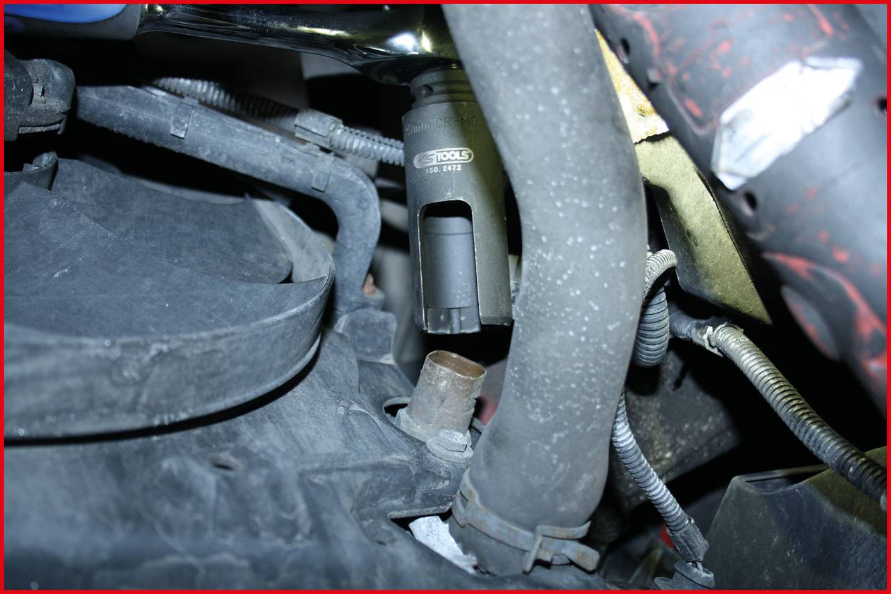 Zbliżenie komory silnika koncentrujące się na metalowym cylindrze i przewodach. Mechaniczne komponenty są wyraźnie widoczne.