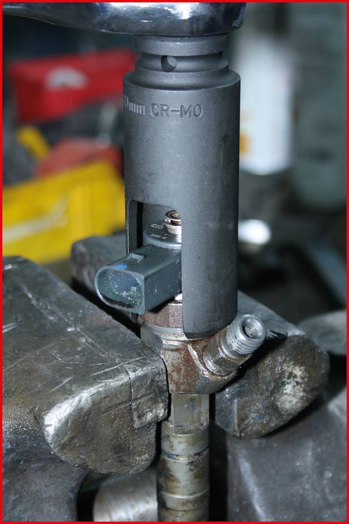 Klucz nasadowy aktywuje czujnik na metalowym elemencie samochodu w warunkach warsztatowych.