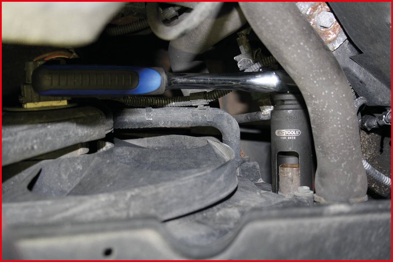 Zbliżenie samochodu, na którym mechanik naprawia silnik. Widoczny jest klucz i części mechaniczne.