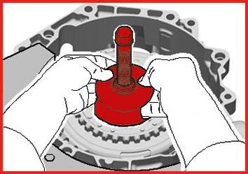 Ręce montują czerwoną śrubę w szarym otworze części maszyny.