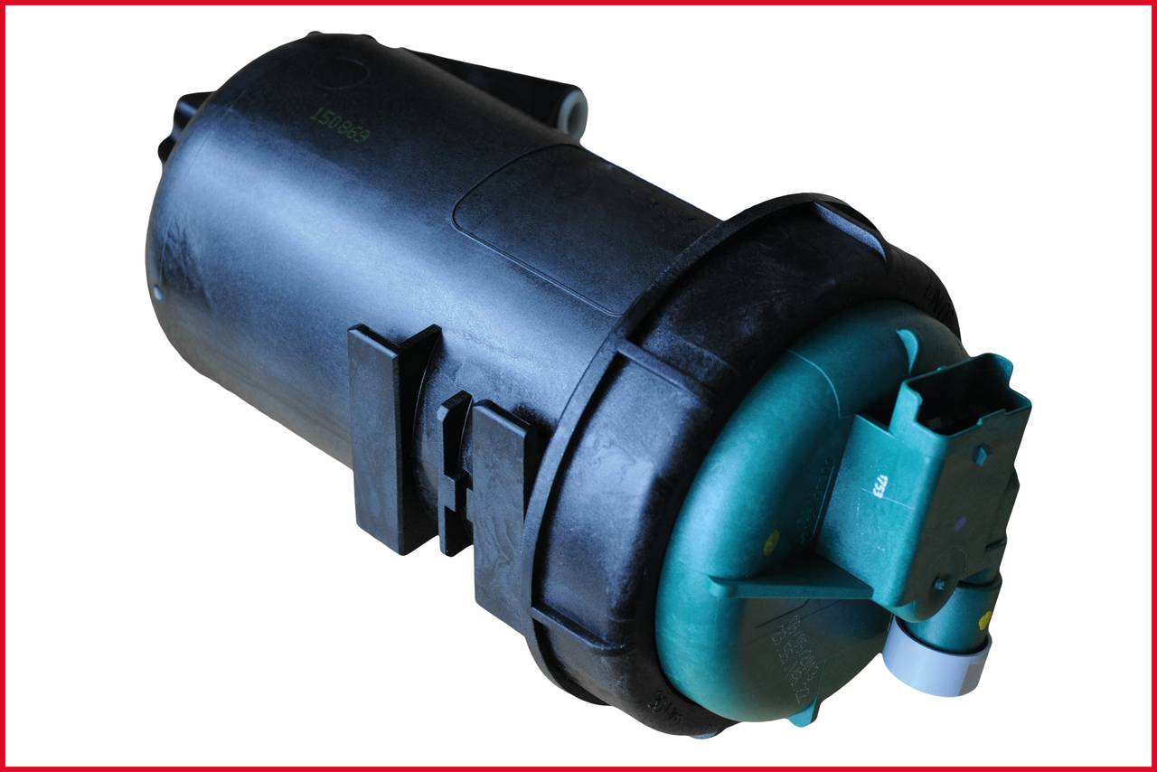 Czarny cylindryczny element z zieloną nakładką i złączem, prawdopodobnie część mechanicznego lub elektronicznego urządzenia.