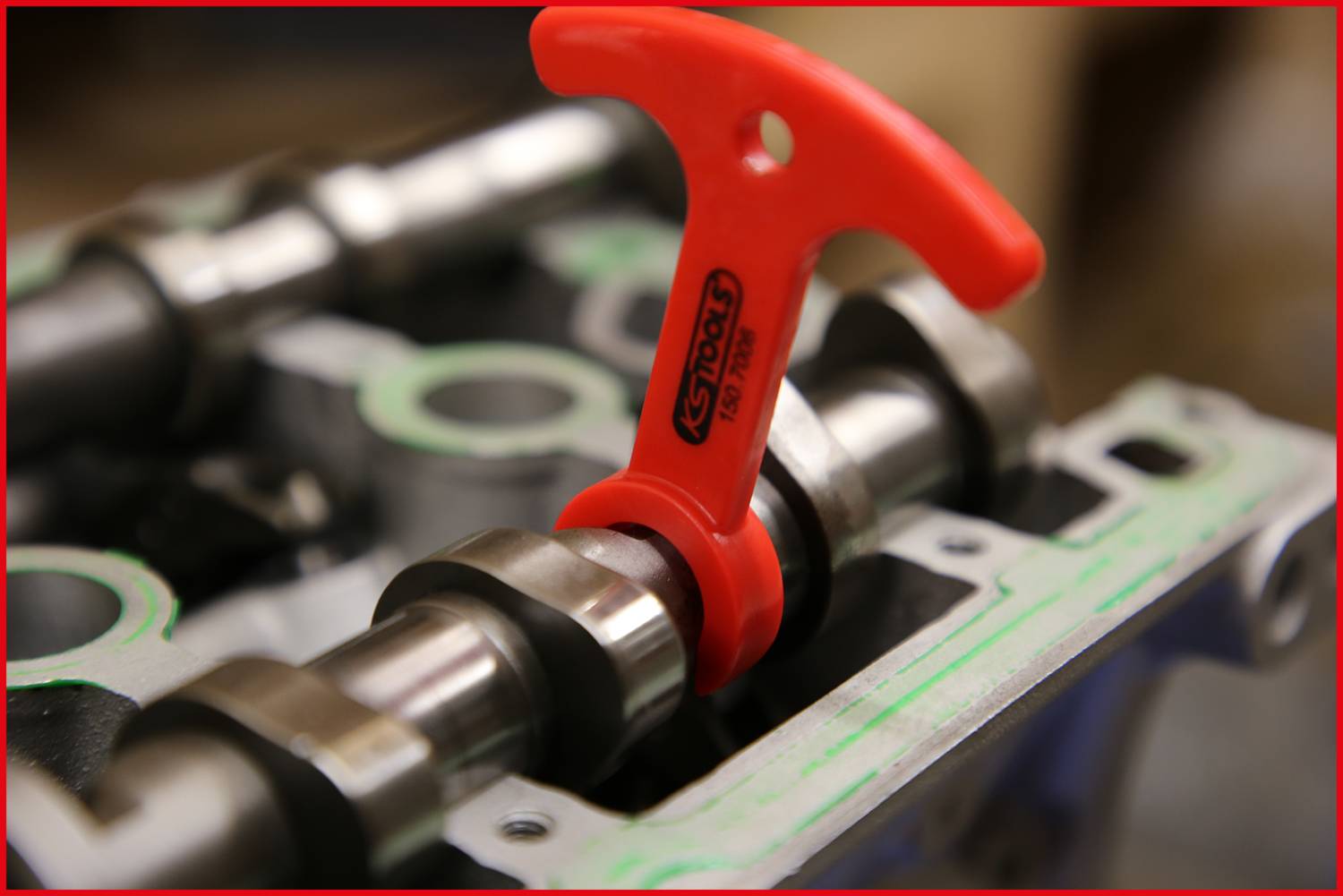 Czerwona plastikowa rękojeść na wałku rozrządu, oznaczona napisem 'Camcheck'. Narzędzie do sprawdzania i regulacji części silnika.