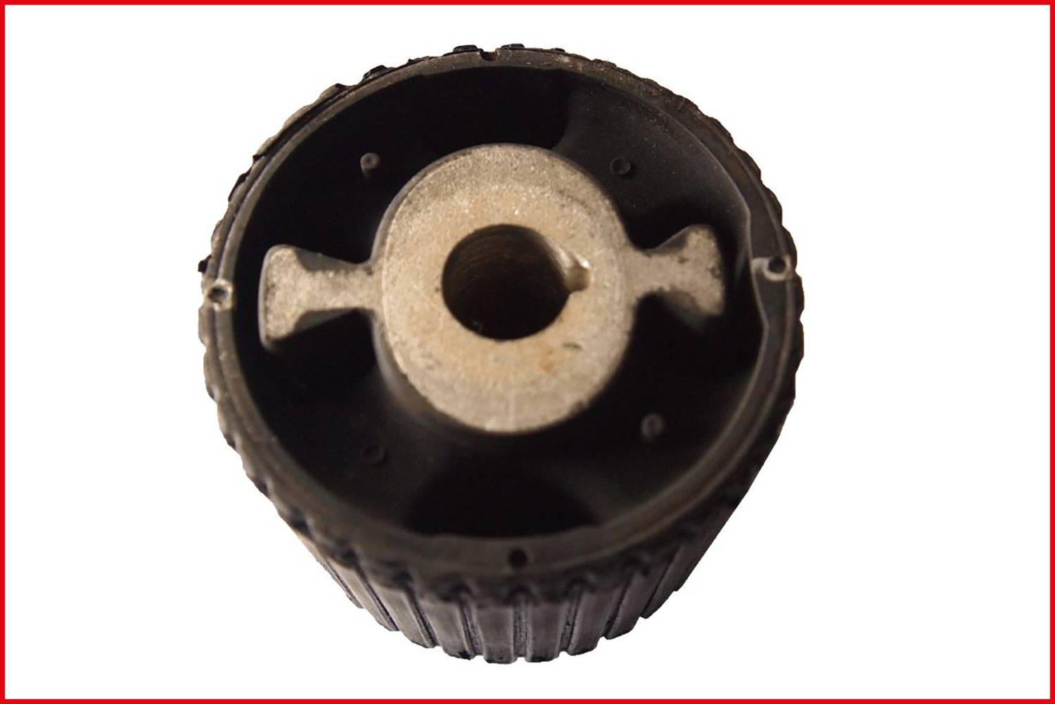 Czarny, żłobkowany element z rdzeniem metalowym, prawdopodobnie koło zębate lub rolka, sfotografowany z góry.