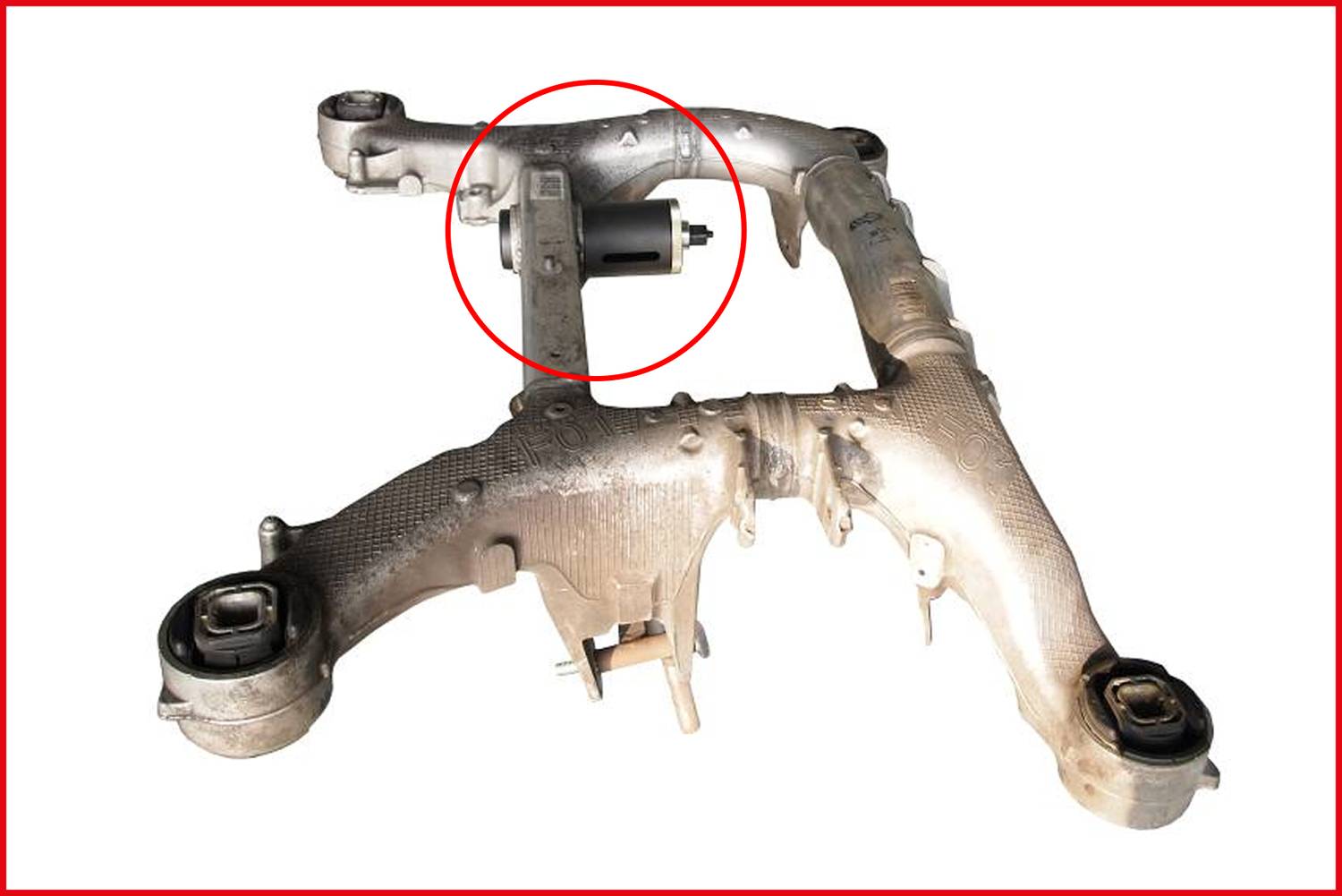 Metalowy tylny wahacz osi pojazdu ze składnikami gumowymi i metalowymi, z dodatkowym wyróżnionym elementem pośrodku.