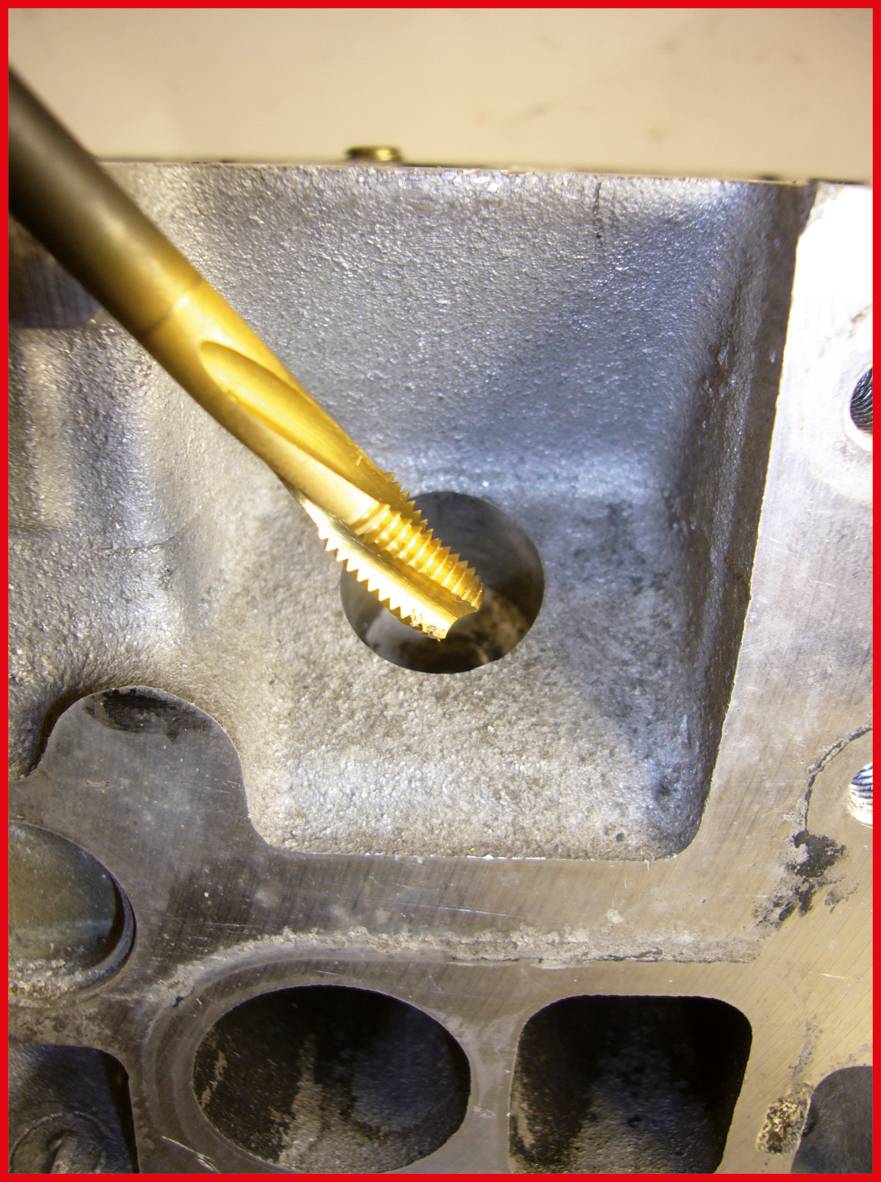 Złoty gwintownik wytwarza gwint w otworze bloku silnika metalowego.