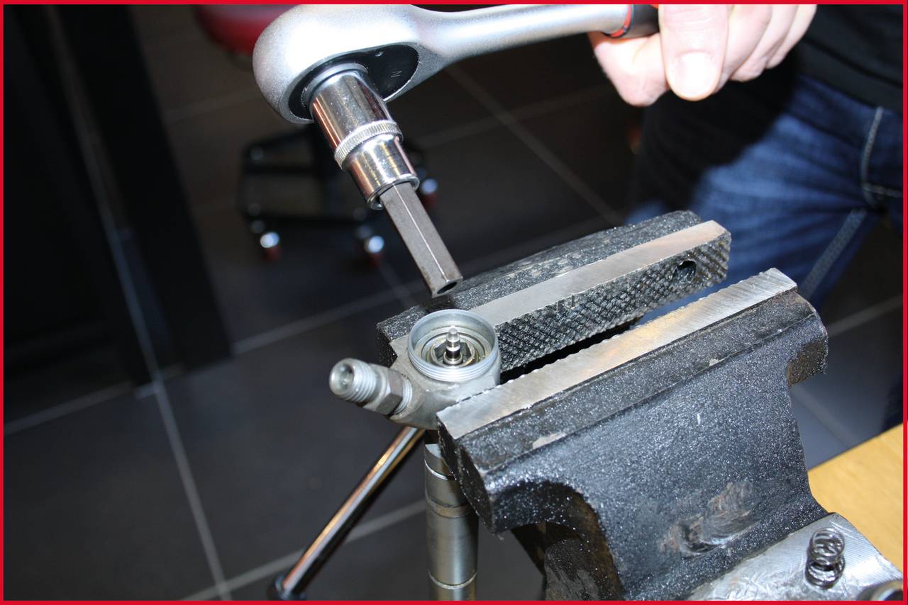 'Osoba dokręca śrubę w imadle za pomocą narzędzia dźwigniowego.'