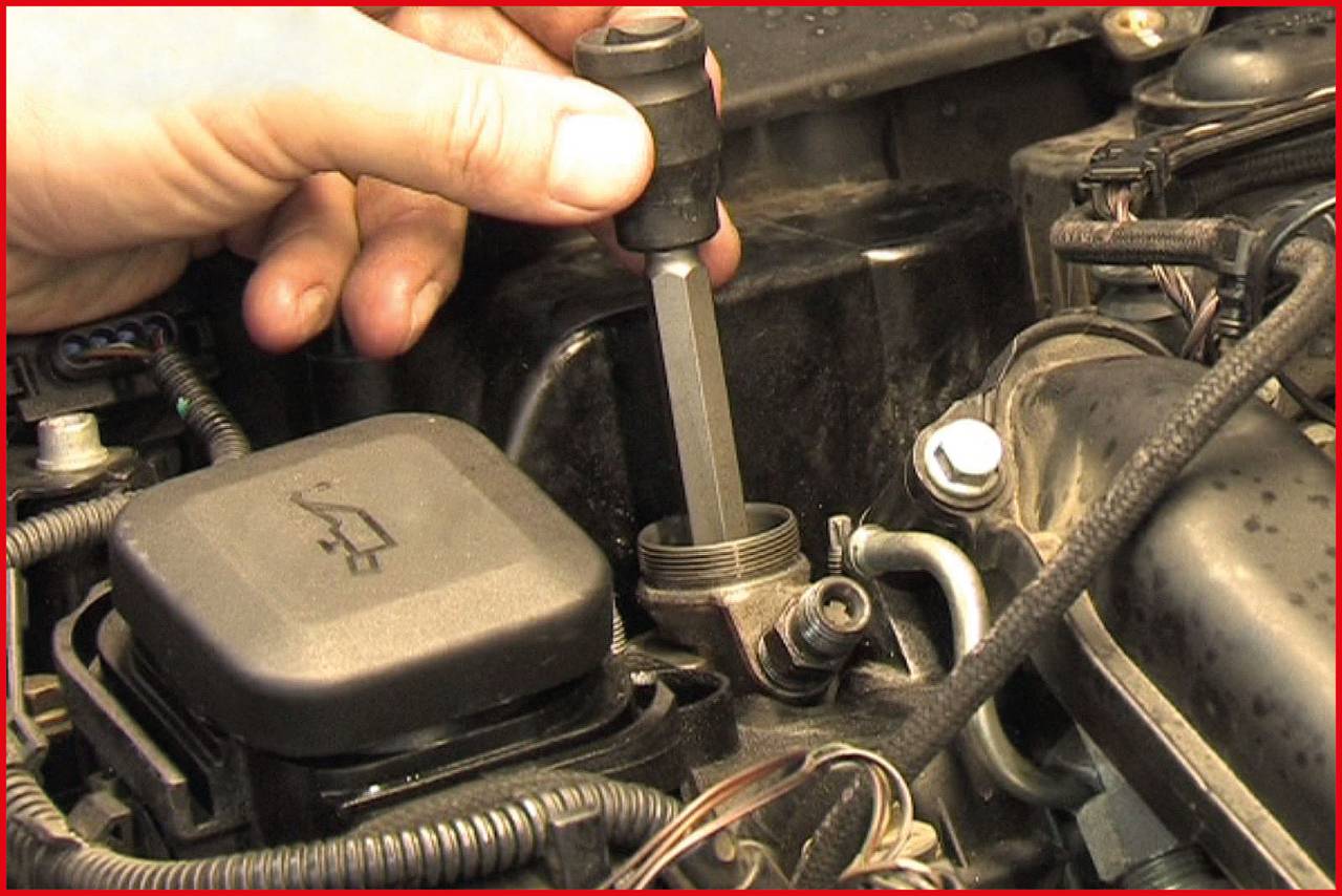 Dłoń używa narzędzia do sprawdzenia części w komorze silnika samochodu.