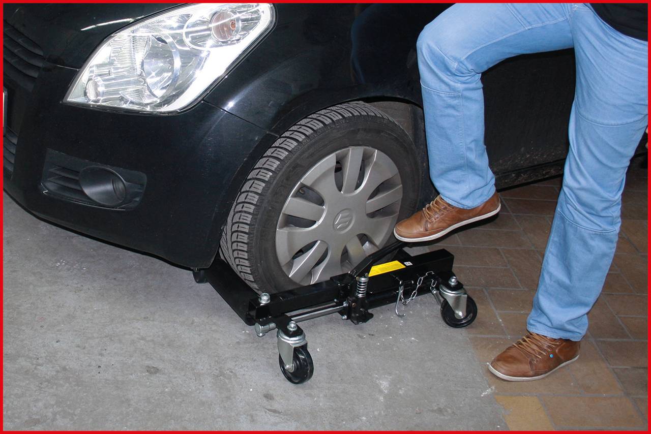 Osoba unosi przednie koło samochodu za pomocą podnośnika, aby łatwiej móc nim manewrować.