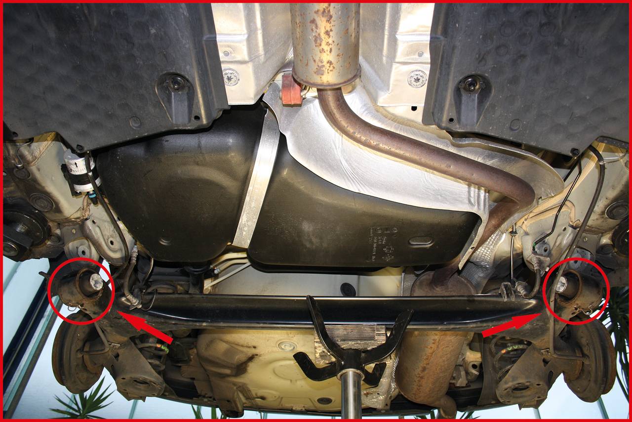 Widok spodu pojazdu na podnośniku. Dwa czerwone kręgi podświetlają specyficzne elementy systemu wydechowego.