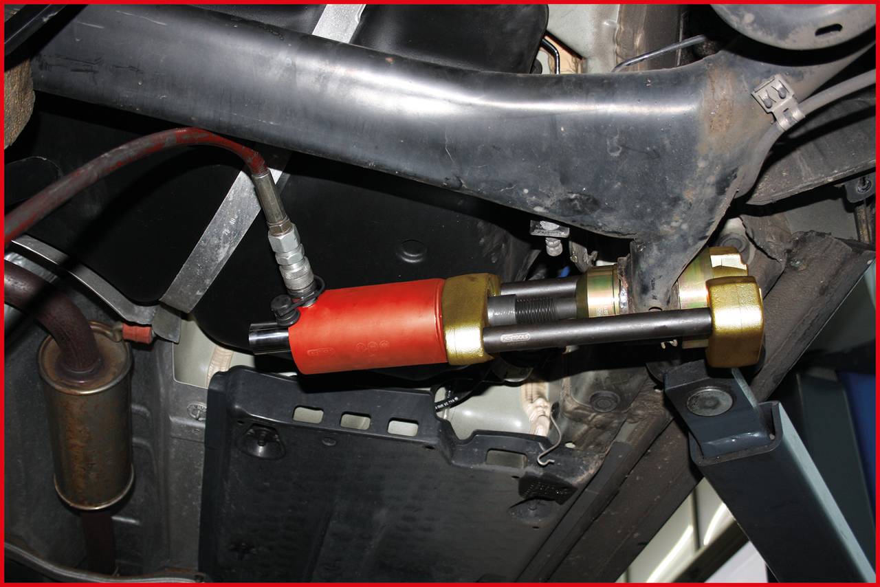 Urządzenie do testowania amortyzatorów sprawdza zawieszenie pojazdu, przenosząc wibracje na jedną z osi. Widok od spodu samochodu.