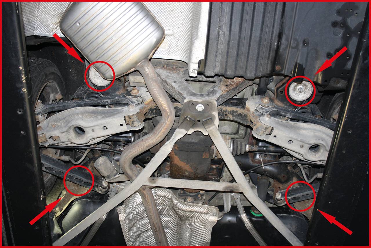 Spód samochodu z zaznaczonymi obszarami. Strzałki i kręgi podkreślają miejsca do inspekcji lub naprawy.