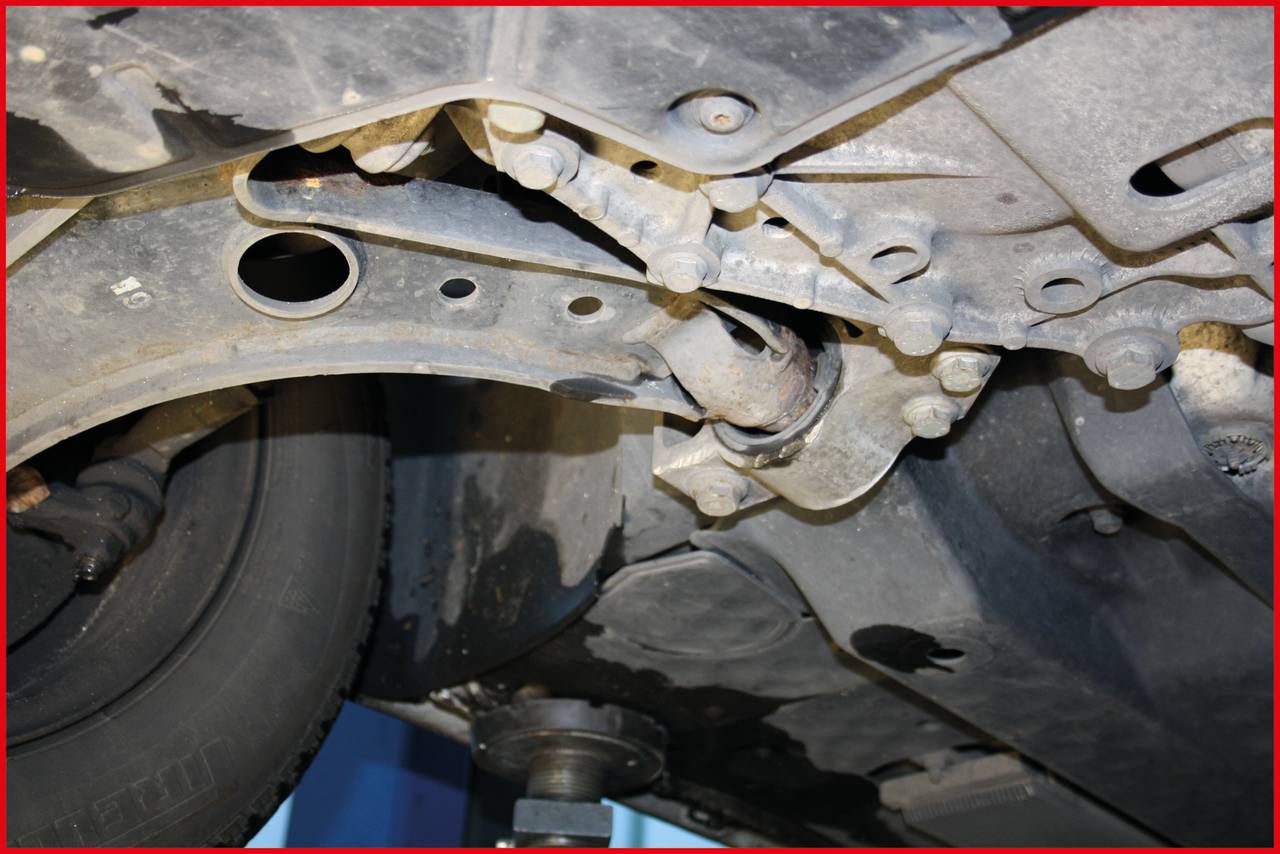 Spód pojazdu na podnośniku, widoczne podwozie z kołem i elementami zawieszenia, w tle rozmyte tło.