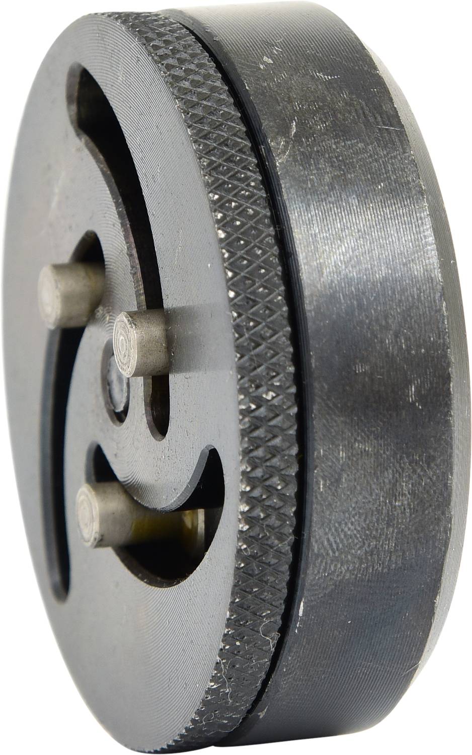 Okrągły element mechaniczny wykonany z metalu, posiadający kilka sworzni i wycięć, prawdopodobnie stanowiący część większego mechanizmu.