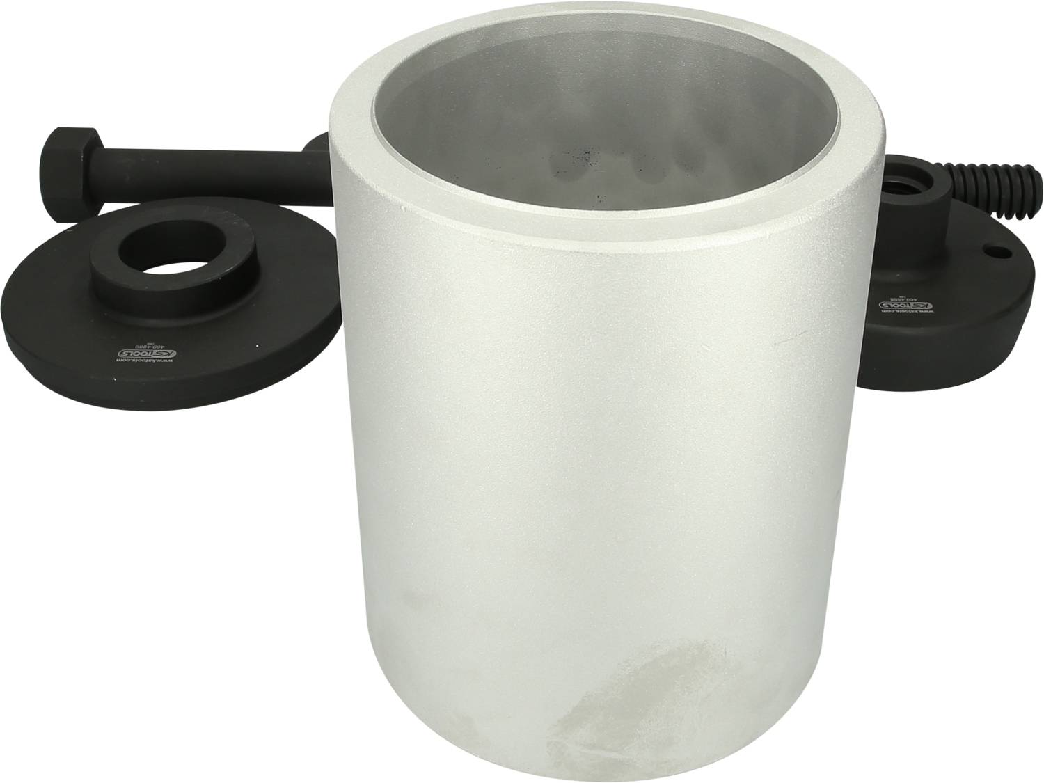 Srebrny metalowy pojemnik z odkrytą pokrywą, otoczony czarnymi elementami mechanicznymi, umieszczony na neutralnym podłożu.