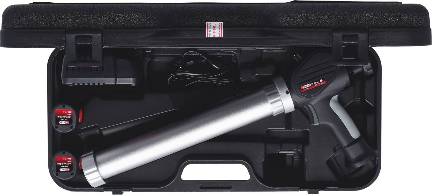 Przenośny, elektryczny, akumulatorowy pistolet do mas uszczelniających w walizce, z ładowarką i dwiema bateriami, zapakowany w czarne pudełko transportowe.