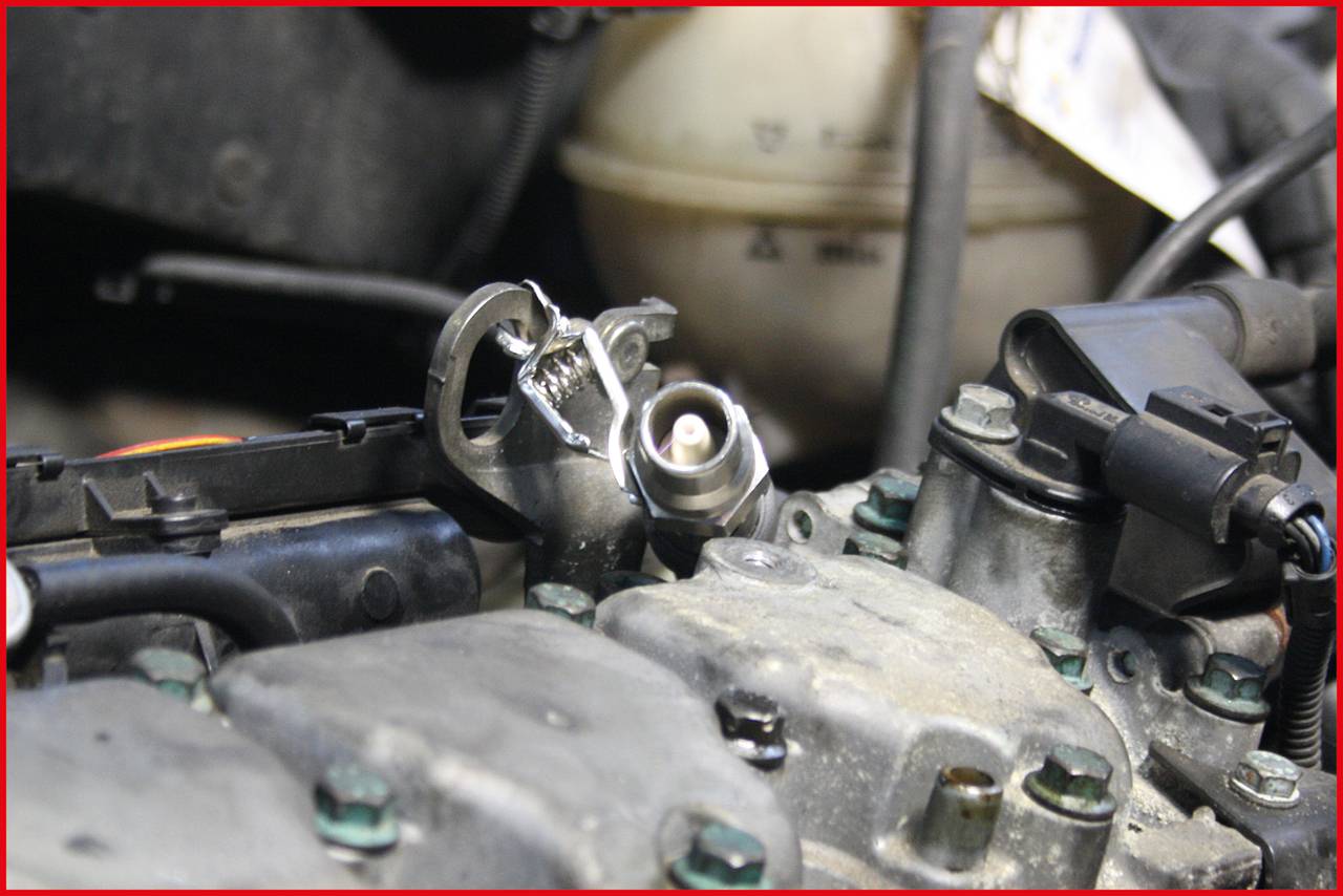 Klucz do świec zapłonowych na bloku silnika wskazuje na trwające prace konserwacyjne silnika pojazdu.