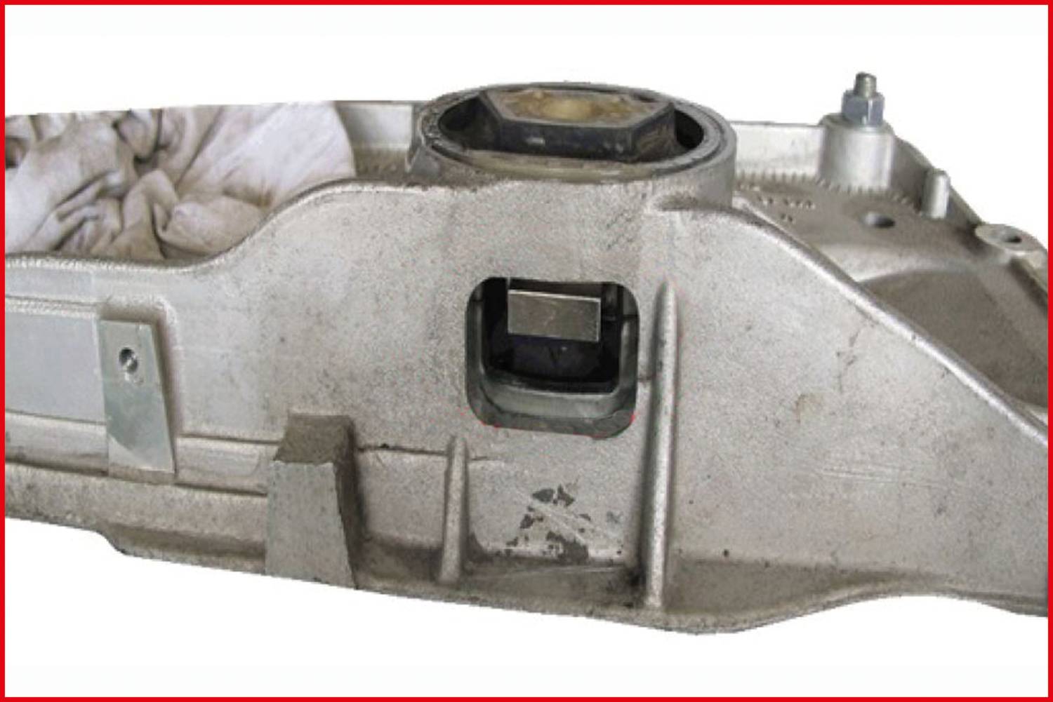 Metalowa obudowa z prostokątnym otworem i widocznym wałem. Na górze widoczna jest część osi z nakrętką sześciokątną.