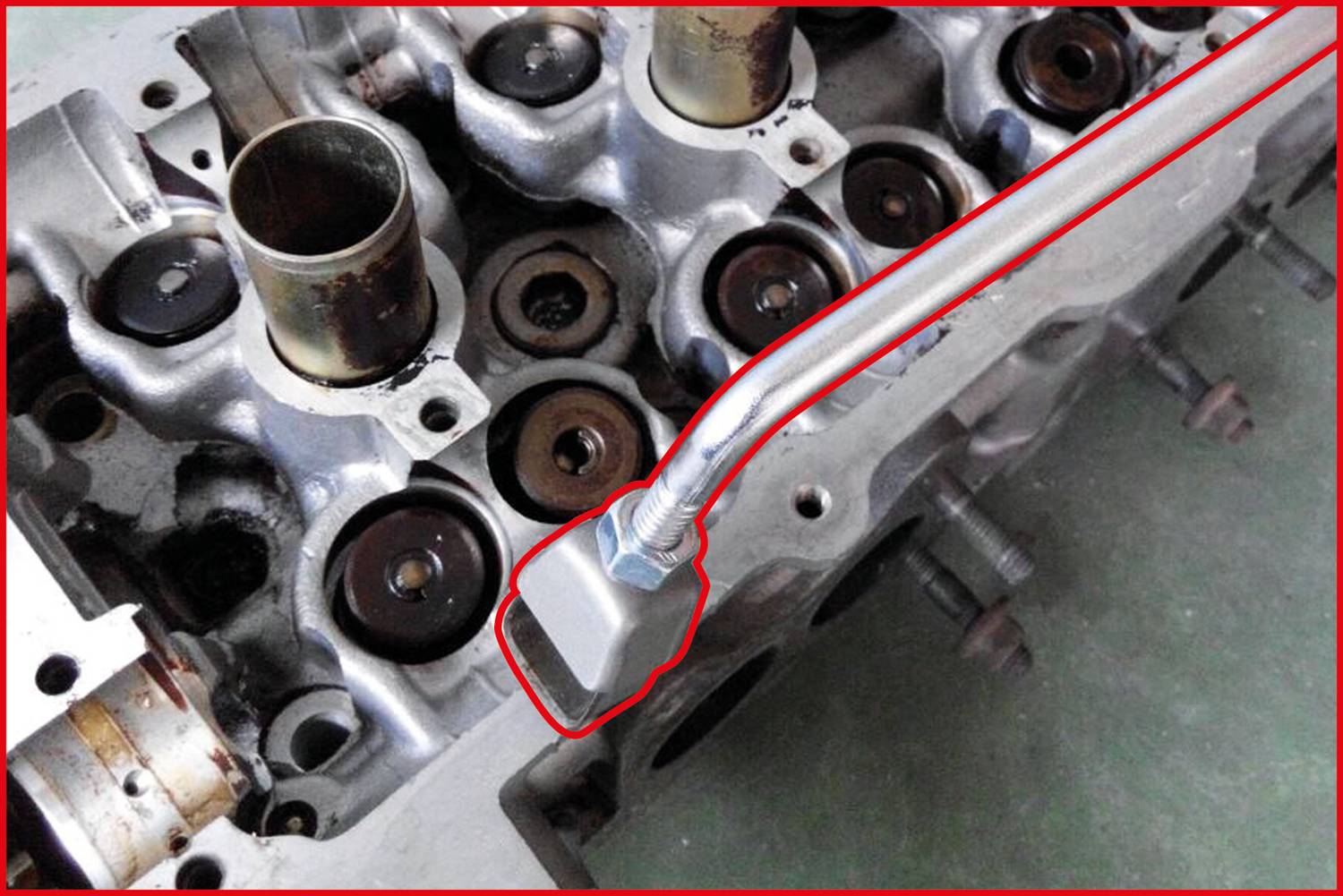 Głowica cylindra silnika zamocowana specjalistycznym narzędziem do usuwania uszczelnień trzpieni zaworowych.