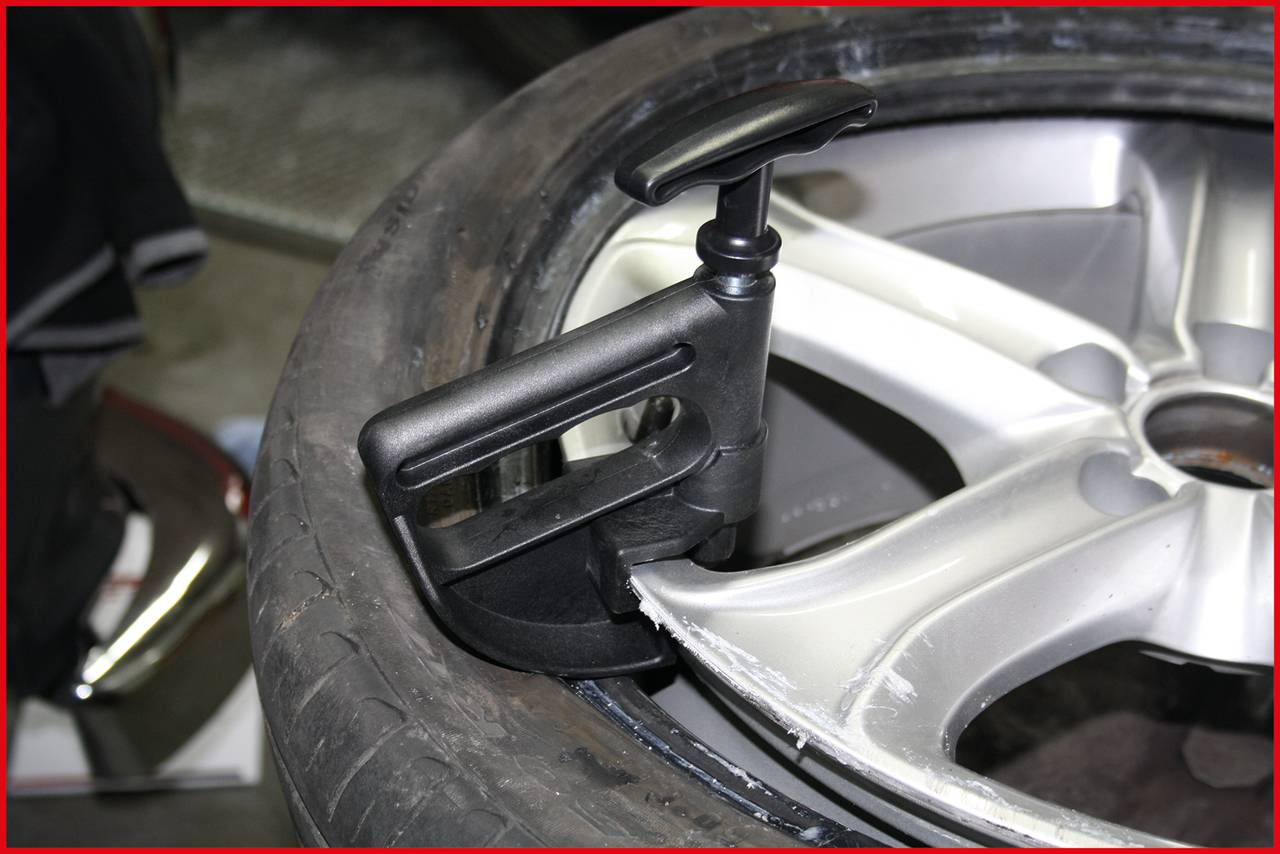 Zbliżenie opony samochodowej zamocowanej na obręczy za pomocą urządzenia do podnoszenia lub stabilizacji.