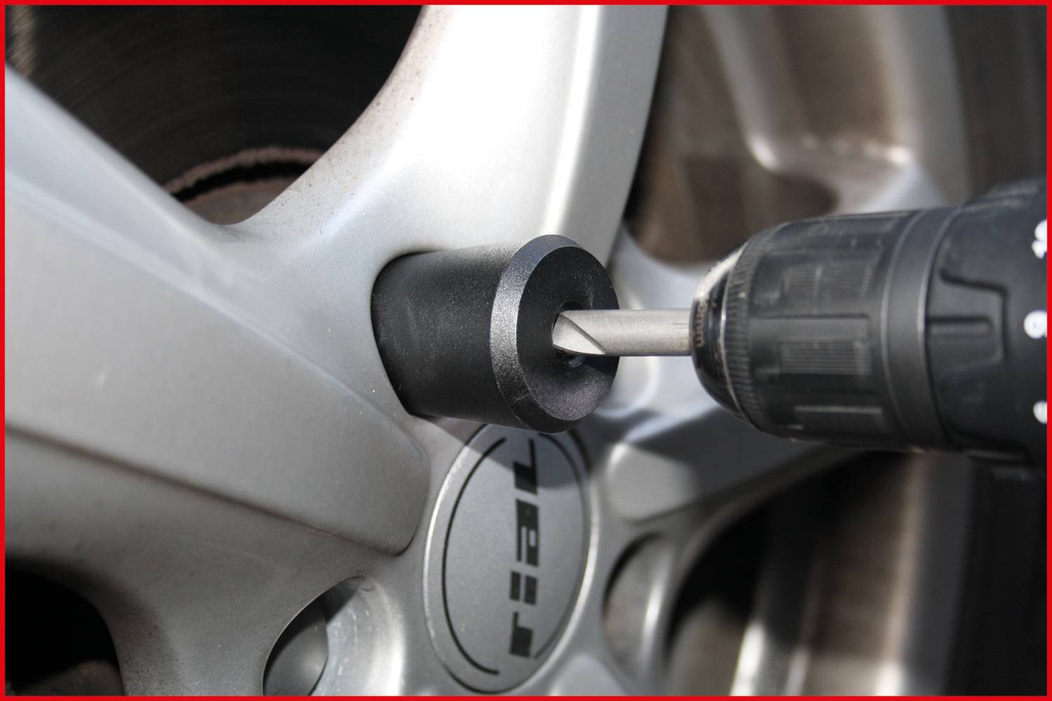 'Śruba koła jest dokręcana śrubokrętem na srebrnym obręczu.'