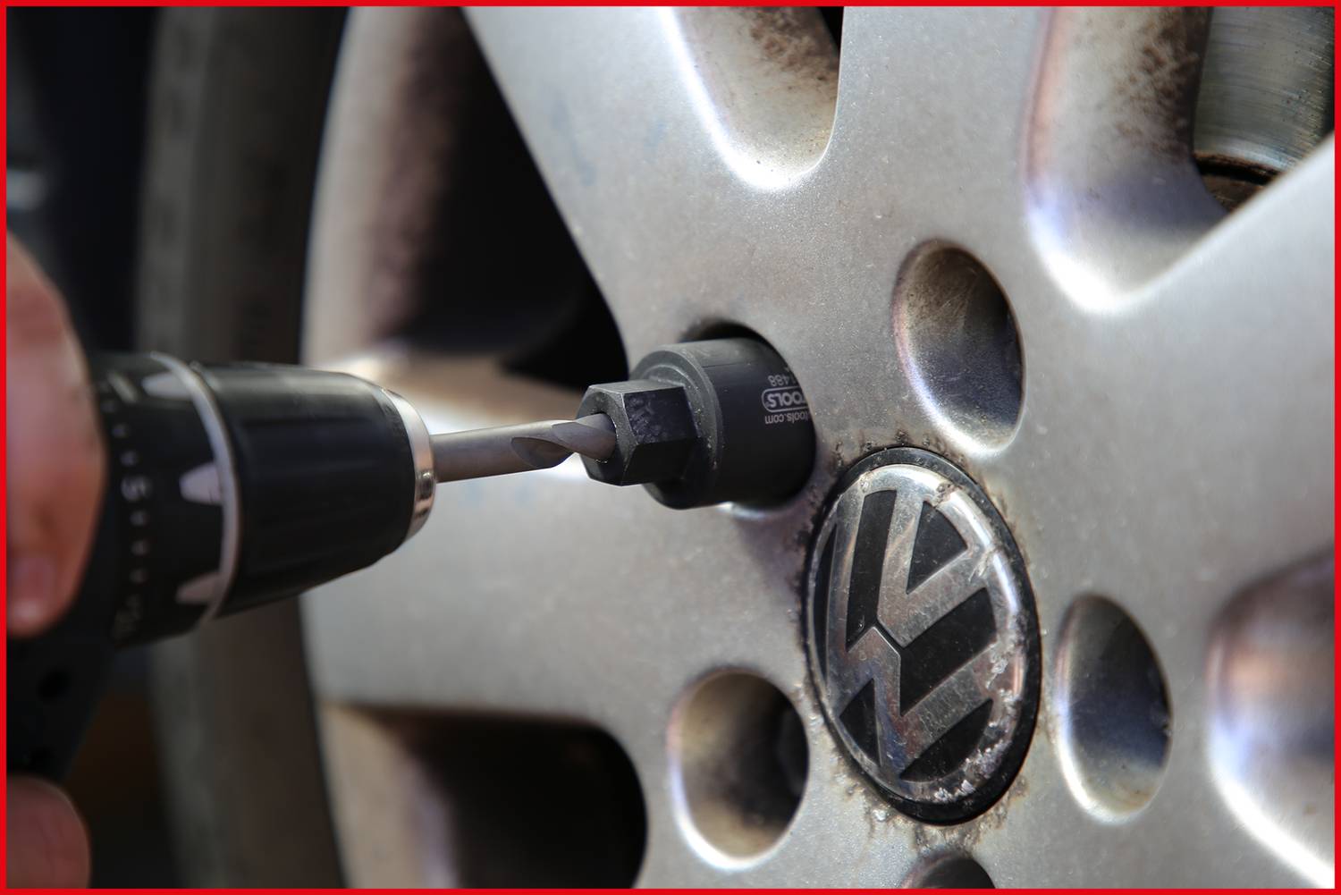 Akumulatorowa wkrętarka dokręca śrubę koła na feldze samochodu popularnej marki.