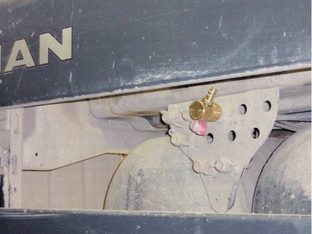 Zbliżenie mocno zabrudzonej ciężarówki z widocznym uchwytem i śrubą mocującą po lewej stronie osłony.