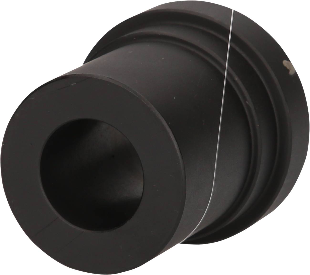 Czarny, cylindryczny element maszyny z dużym otworem centralnym. Posiada gładką powierzchnię i jest wykonany z metalu.