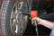 Osoba dokręca śruby koła samochodu wkrętarką pneumatyczną.