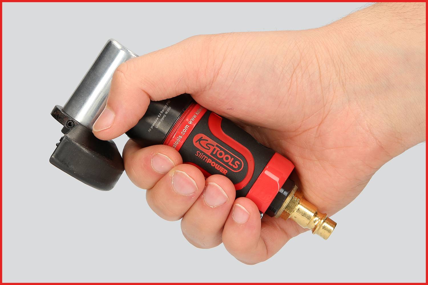 Jedna ręka trzyma czerwone i czarne narzędzie z metalowym końcówką, które pokazuje złącze do sprężonego powietrza.