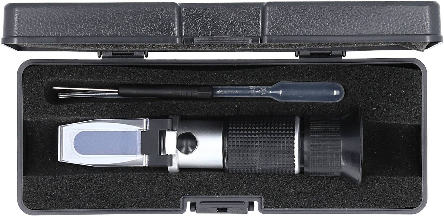 Refraktometr w otwartym etui, towarzyszący pipecie i małemu narzędziu, ułożony na czarnej gąbce.