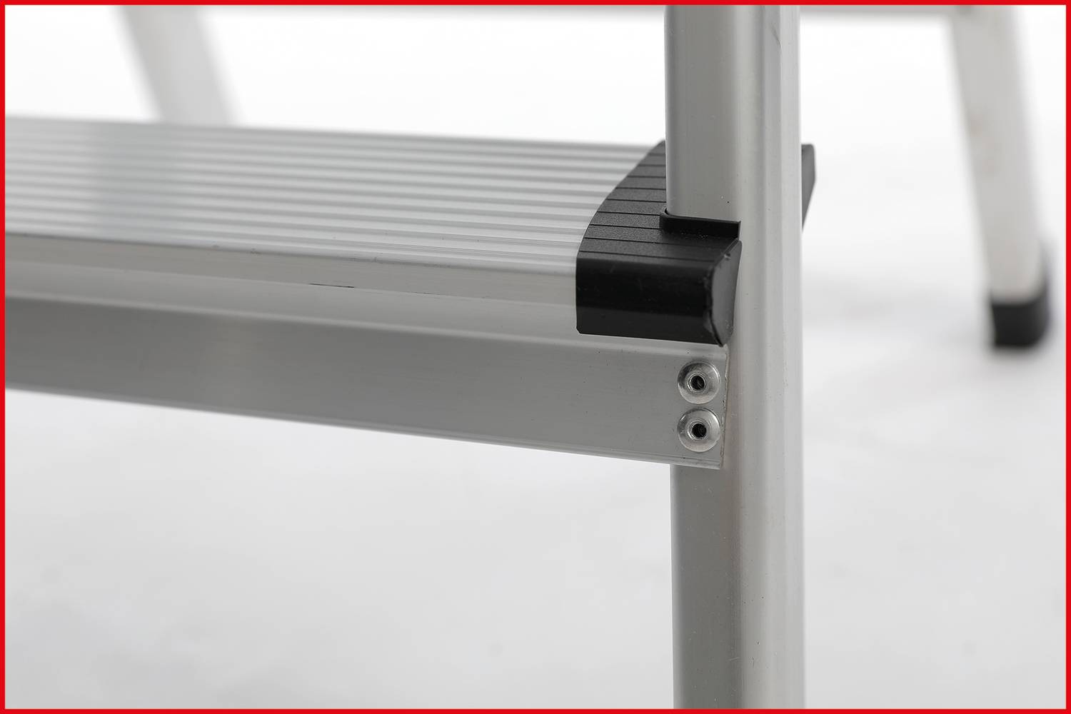 Zbliżenie aluminiowego stopnia z antypoślizgowymi gumowymi narożnikami. Zdjęcie prezentuje stabilność i bezpieczeństwo rozwiązania.