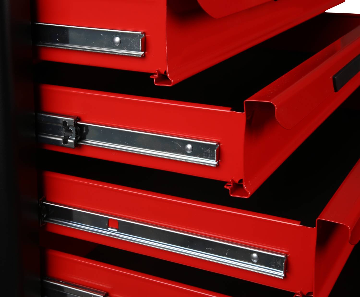 Czerwona szafka narzędziowa z wieloma otwartymi szufladami, częściowo widocznymi. Wysokiej jakości metalowe prowadnice zapewniające stabilność i łatwość obsługi.
