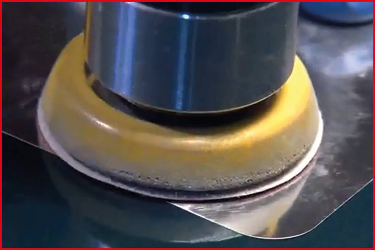 Maszyna poleruje powierzchnię metalową za pomocą obrotowej tarczy; zbliżenie pracy w kontekście przemysłowym.