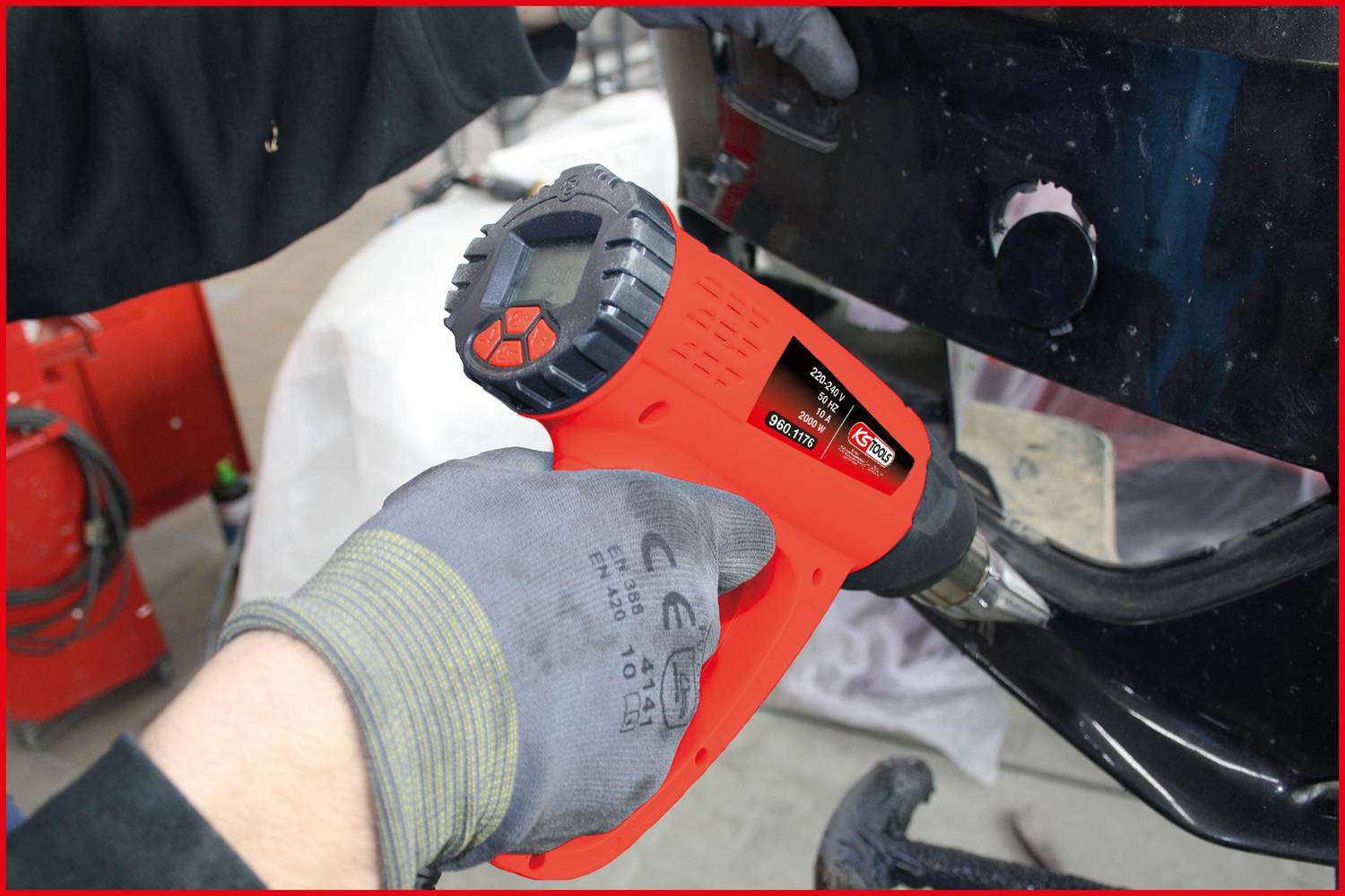 Osoba używa czerwono-czarnego pistoletu na gorące powietrze do obróbki materiału samochodowego. Narzędzie posiada wyświetlacz i elementy sterujące.