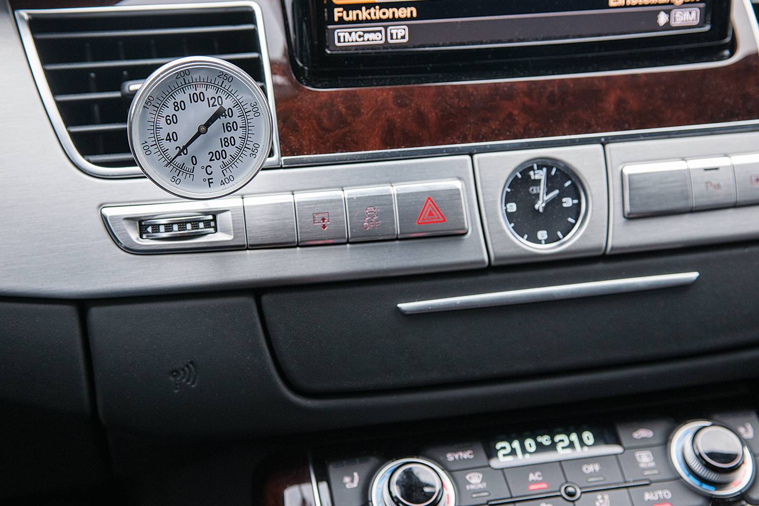 Autotachometr z wyświetlaczem temperatury, wskazujący 110°C. Widoczne są sterowniki bezpieczeństwa i klimatyzacji. W tle wnętrze samochodu.