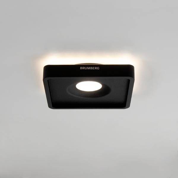 Kwadratowy, czarny reflektor sufitowy z wbudowanym światłem LED, zamontowany na białym suficie i świecący w dół.