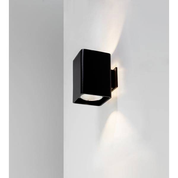 Czarna lampa ścienna, która emituje światło zarówno w górę, jak i w dół, zamontowana na białej ścianie.