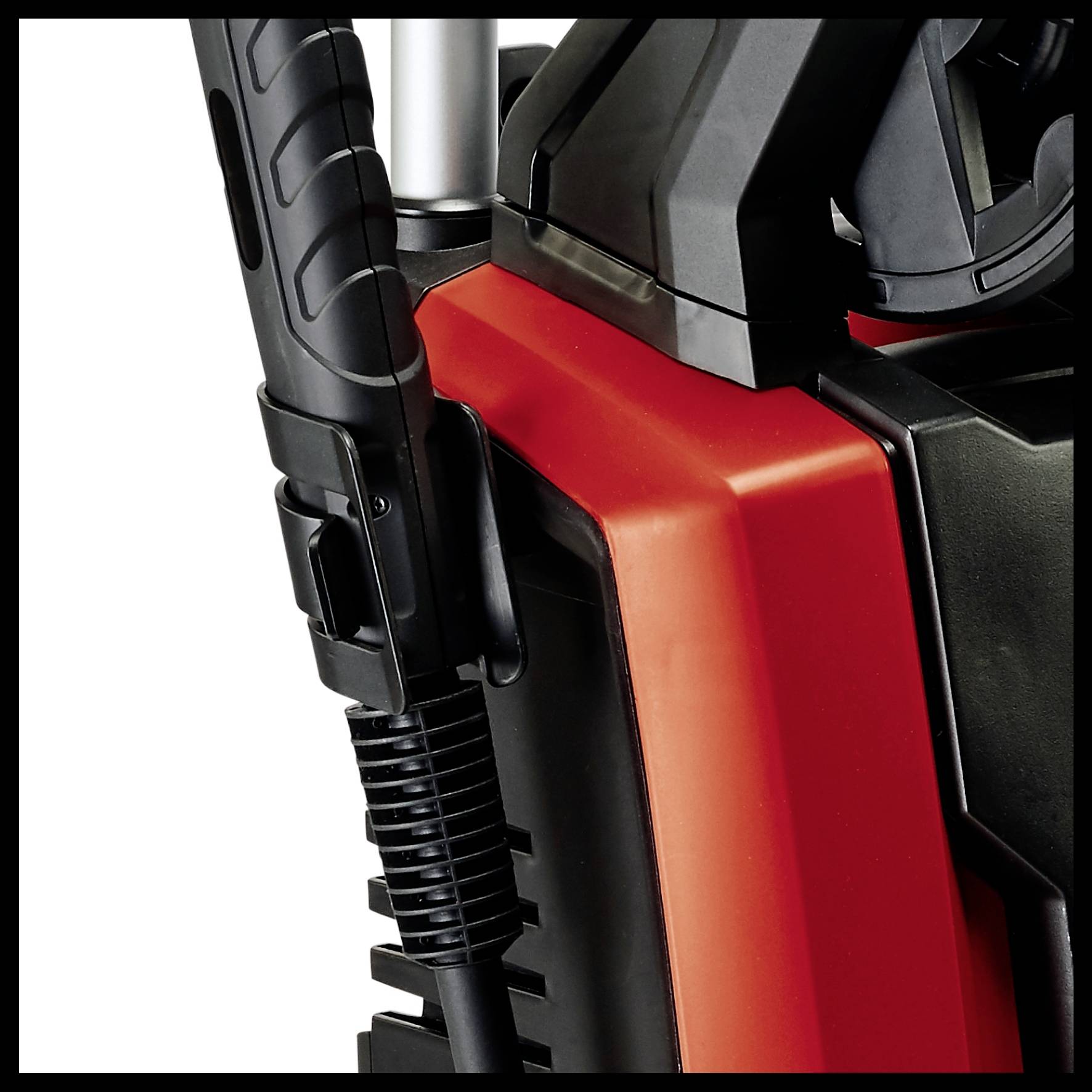 Czerwona myjka ciśnieniowa z czarną rączką i wężem. Nacisk kładziony jest na obsługę i kształt urządzenia.