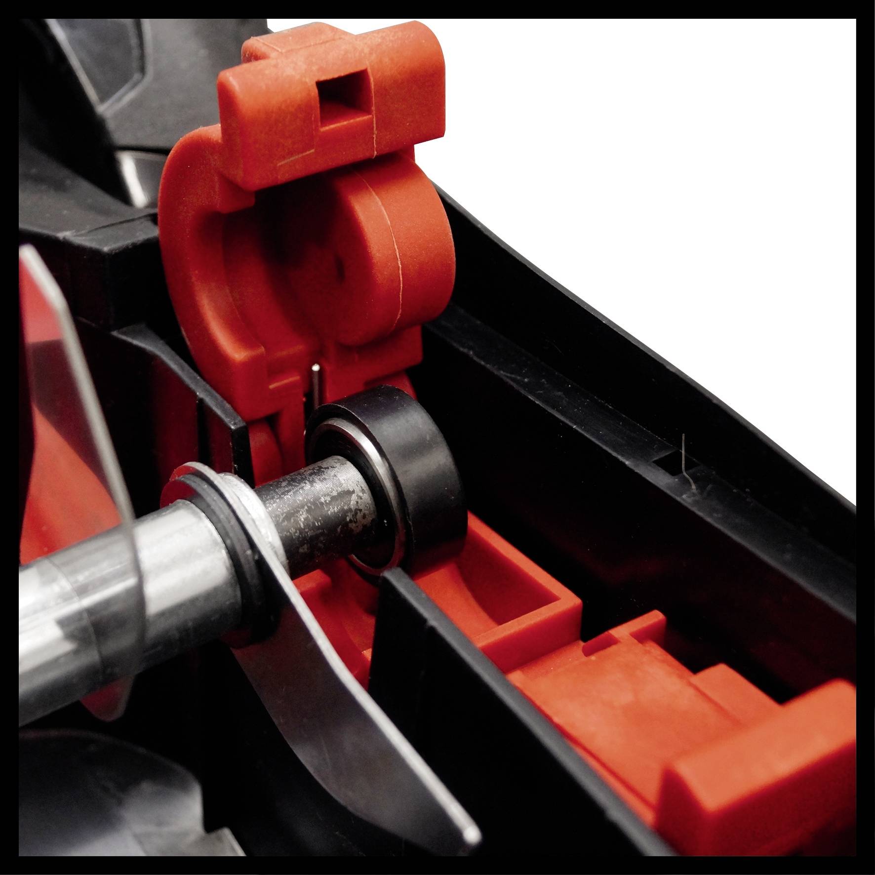 Część czerwono-czarnego elementu maszynowego z srebrnym metalowym prętem i częściami z tworzywa sztucznego istotnymi dla połączenia.