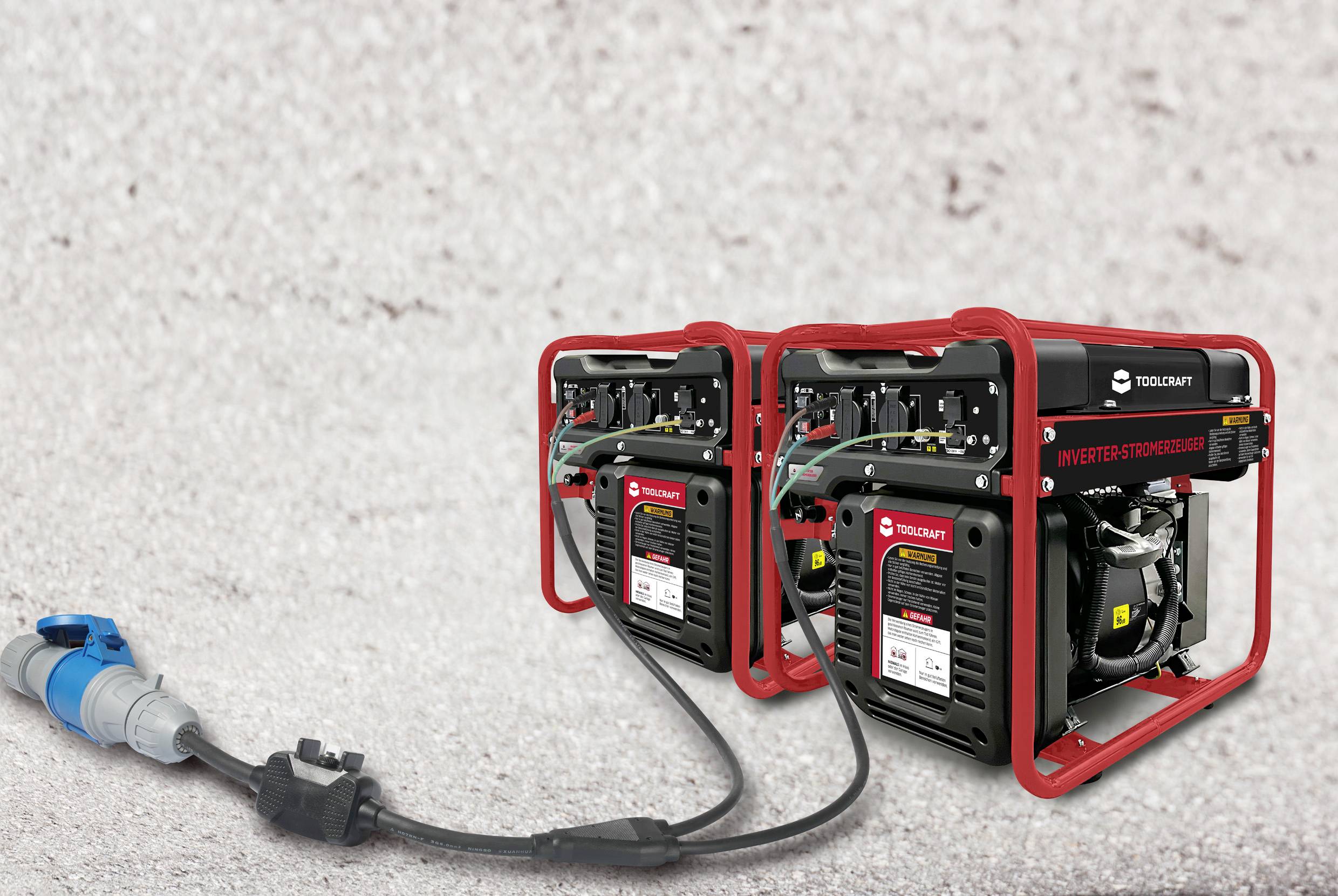 Dwa przenośne generatory są połączone przewodami i stoją na żwirowym podłożu.