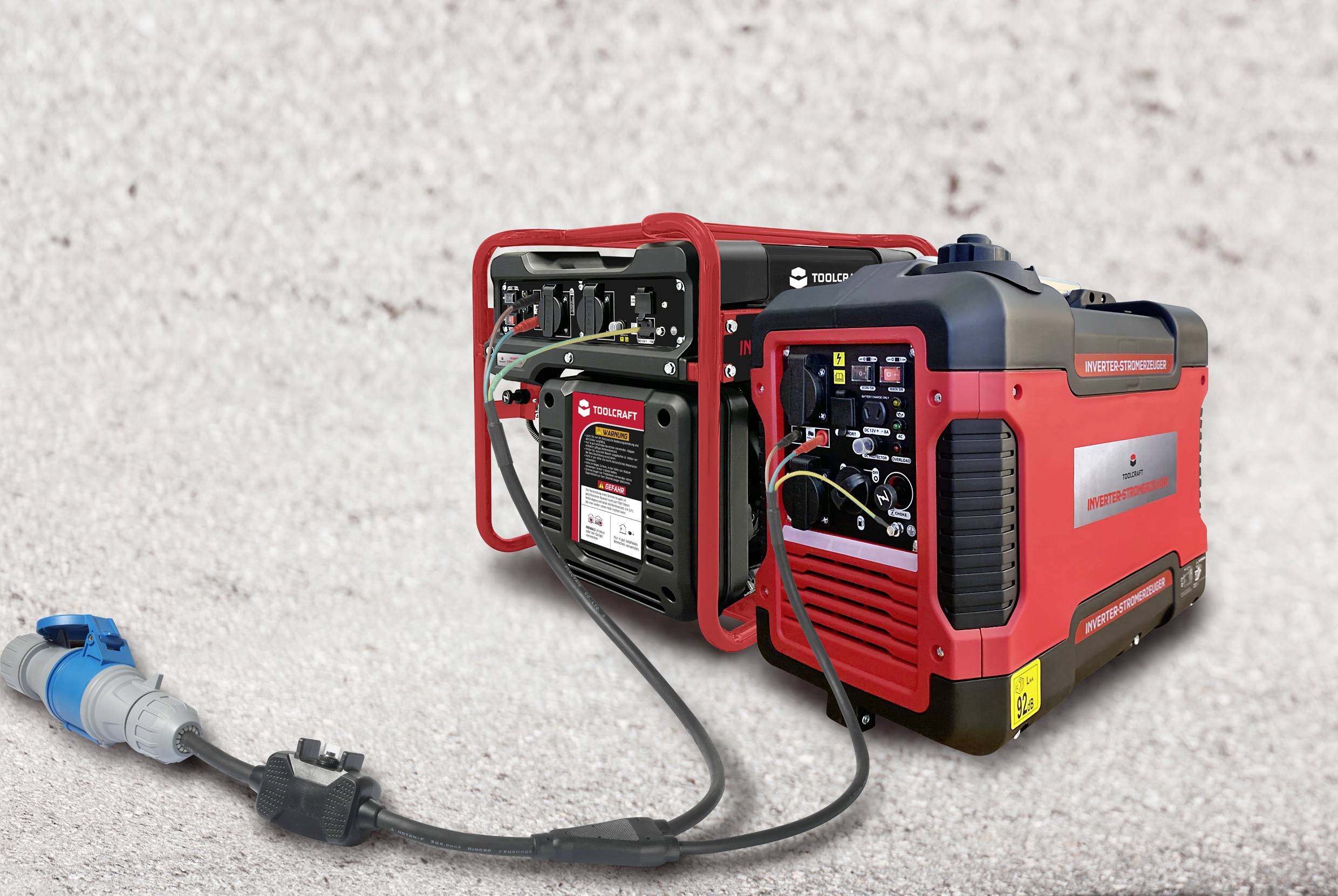 Czerwony agregat prądotwórczy stoi na betonowej podłodze. Jest podłączony niebieskim przewodem elektrycznym i posiada kilka złączy.