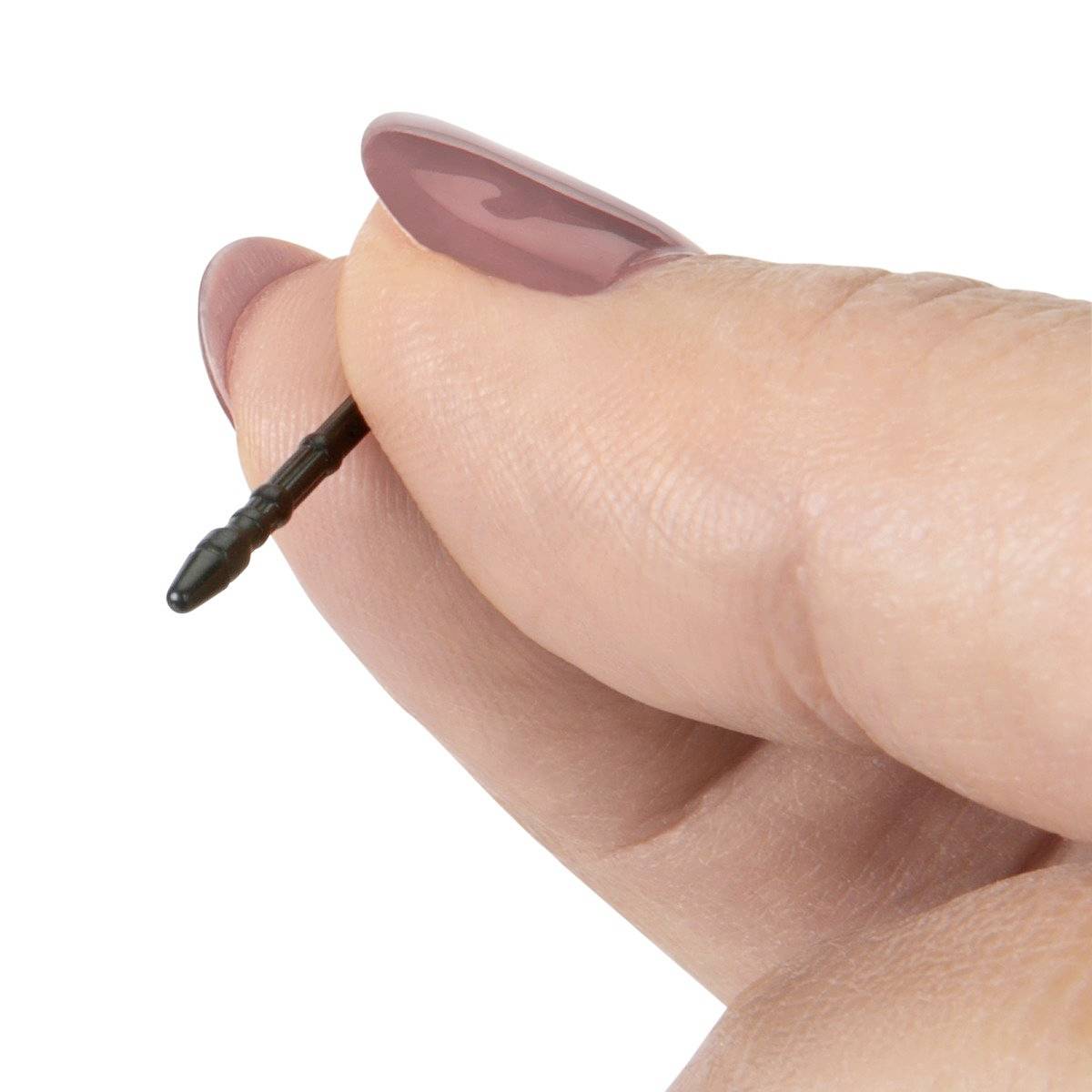 Dłoń trzyma mały, czarny, spiczasty przedmiot między kciukiem a palcem wskazującym.