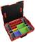 Otwarty czerwony pojemnik z asortymentem, posiadający kilka komór o różnych rozmiarach. Zawiera szare, żółte, zielone i niebieskie wkładki.